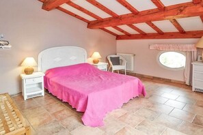 A bedroom with a bed, two bedside tables, a chair, a radiator, and a window. - Villa in Carqueiranne with swimming pool (Carqueiranne)