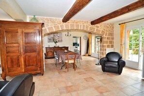 A dining area with a stone archway, wooden furniture, and a view of greenery outside. - Villa in Carqueiranne with swimming pool (Carqueiranne)