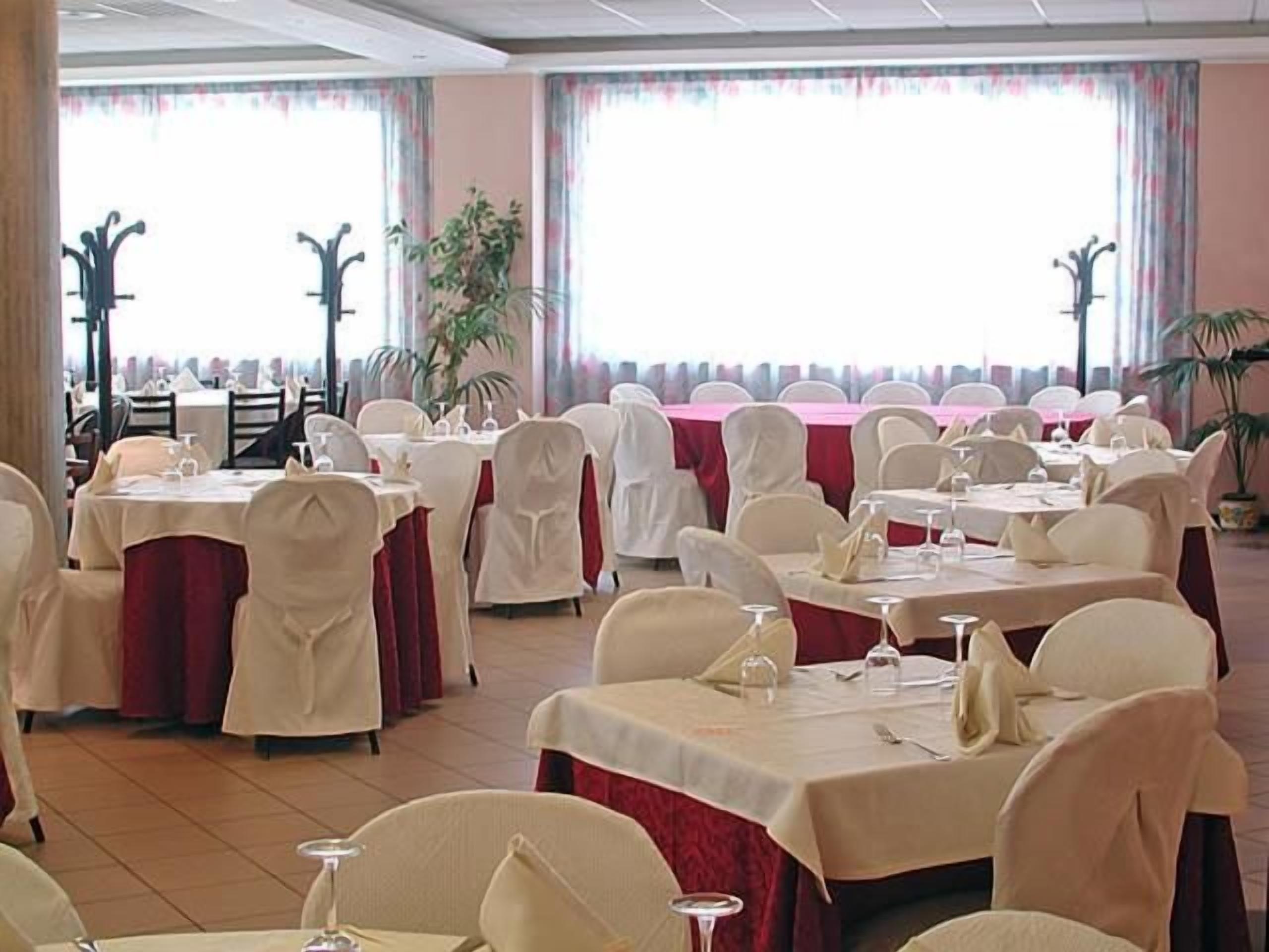 Un salón de banquetes con mesas redondas, sillas y vista al mar a través de amplios ventanales.