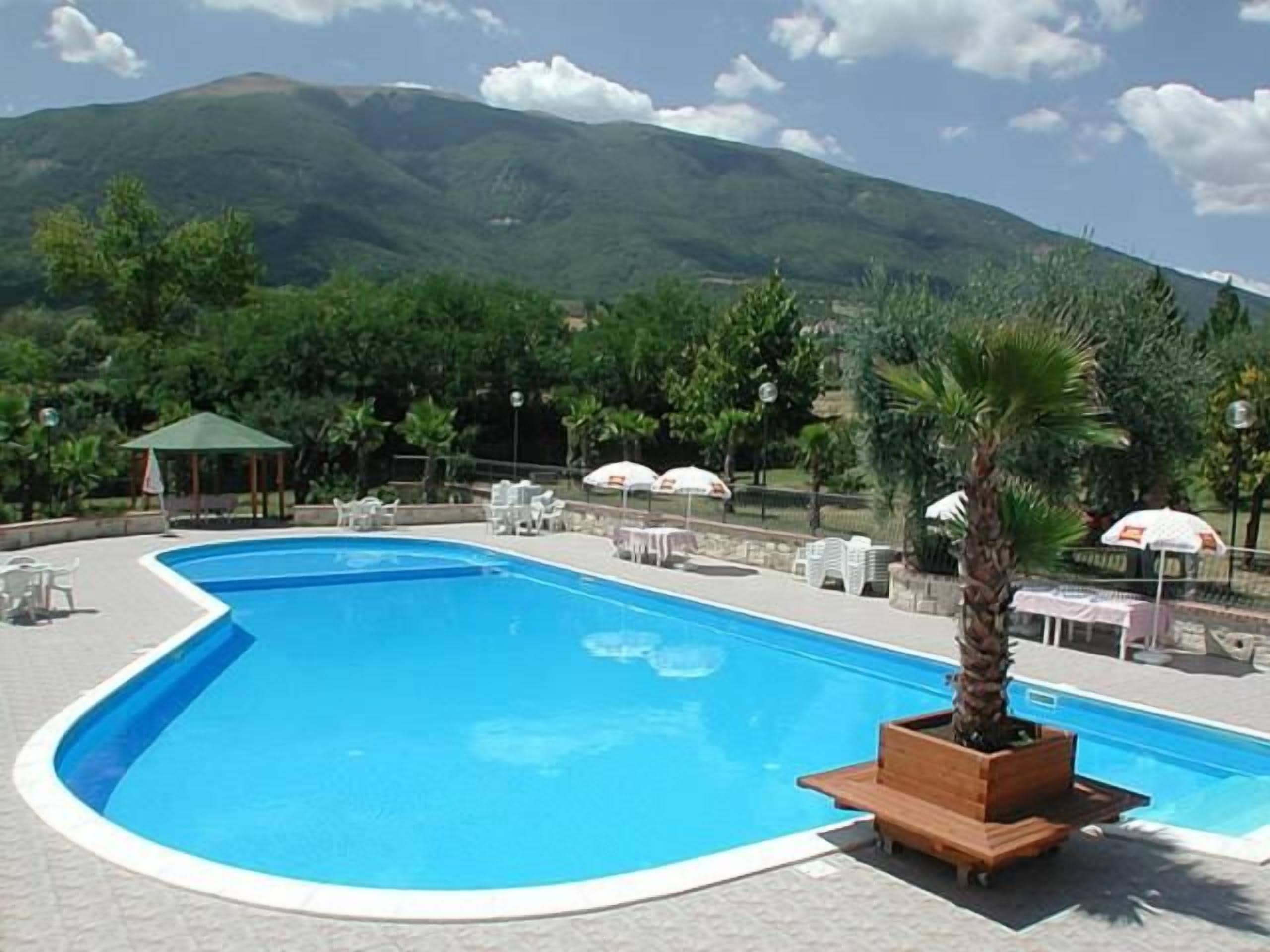 Une piscine avec vue sur les montagnes, entourée de chaises longues et de parasols.