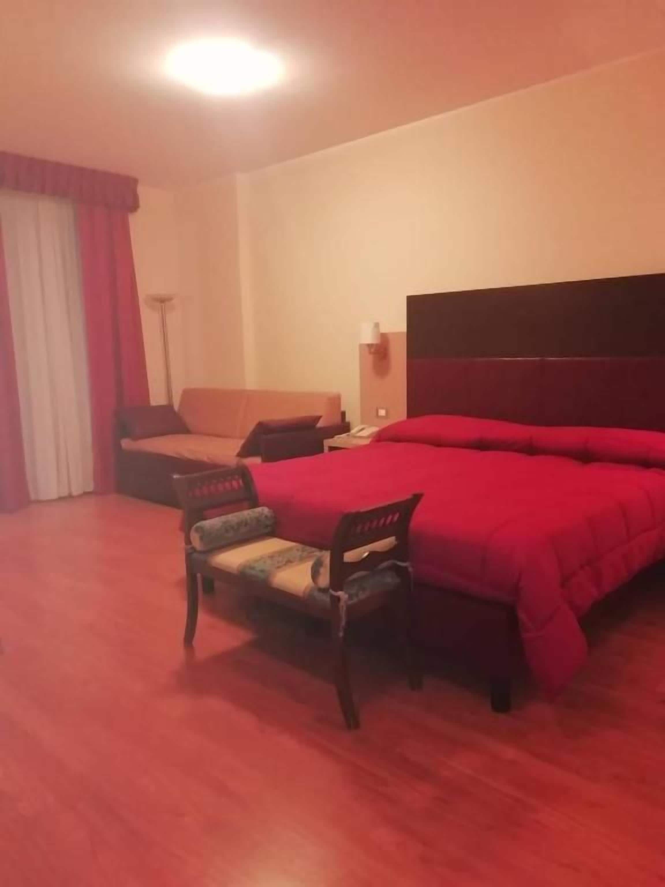 Une chambre d’hôtel avec un lit, un bureau, une chaise et une lampe.