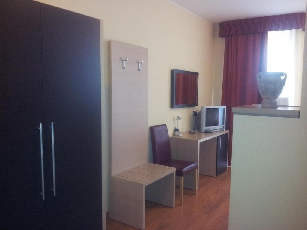 Una camera d'albergo compatta con angolo cottura, televisione, zona pranzo e armadio.
