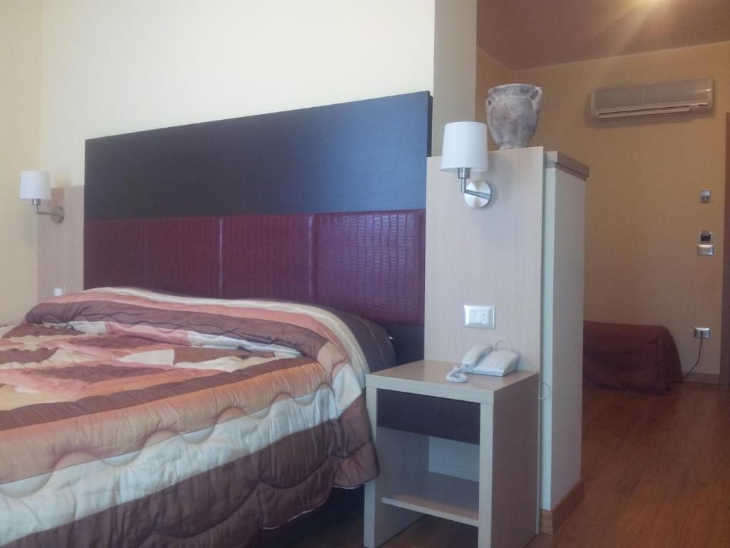 Une chambre d’hôtel avec un lit, une table de chevet, une lampe et un petit meuble.