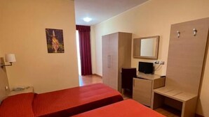 Et hotelværelse med to senge, et skrivebord, et spejl og en garderobe.