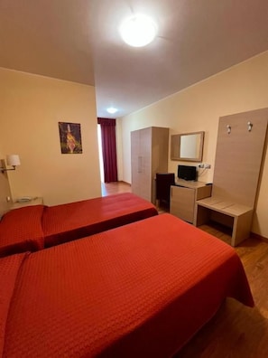 Una habitación de hotel con dos camas, un escritorio, un espejo y un armario.