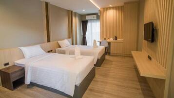 A hotel room with two beds, a desk, a chair, a TV, and a window with curtains.