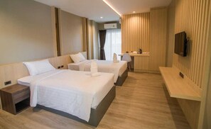 A hotel room with two beds, a desk, a chair, a TV, and a window with curtains.