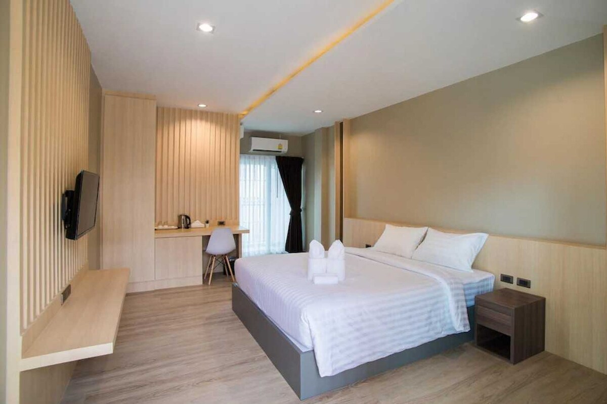 Una habitación de hotel con una cama, una mesita de noche y un escritorio con una silla.