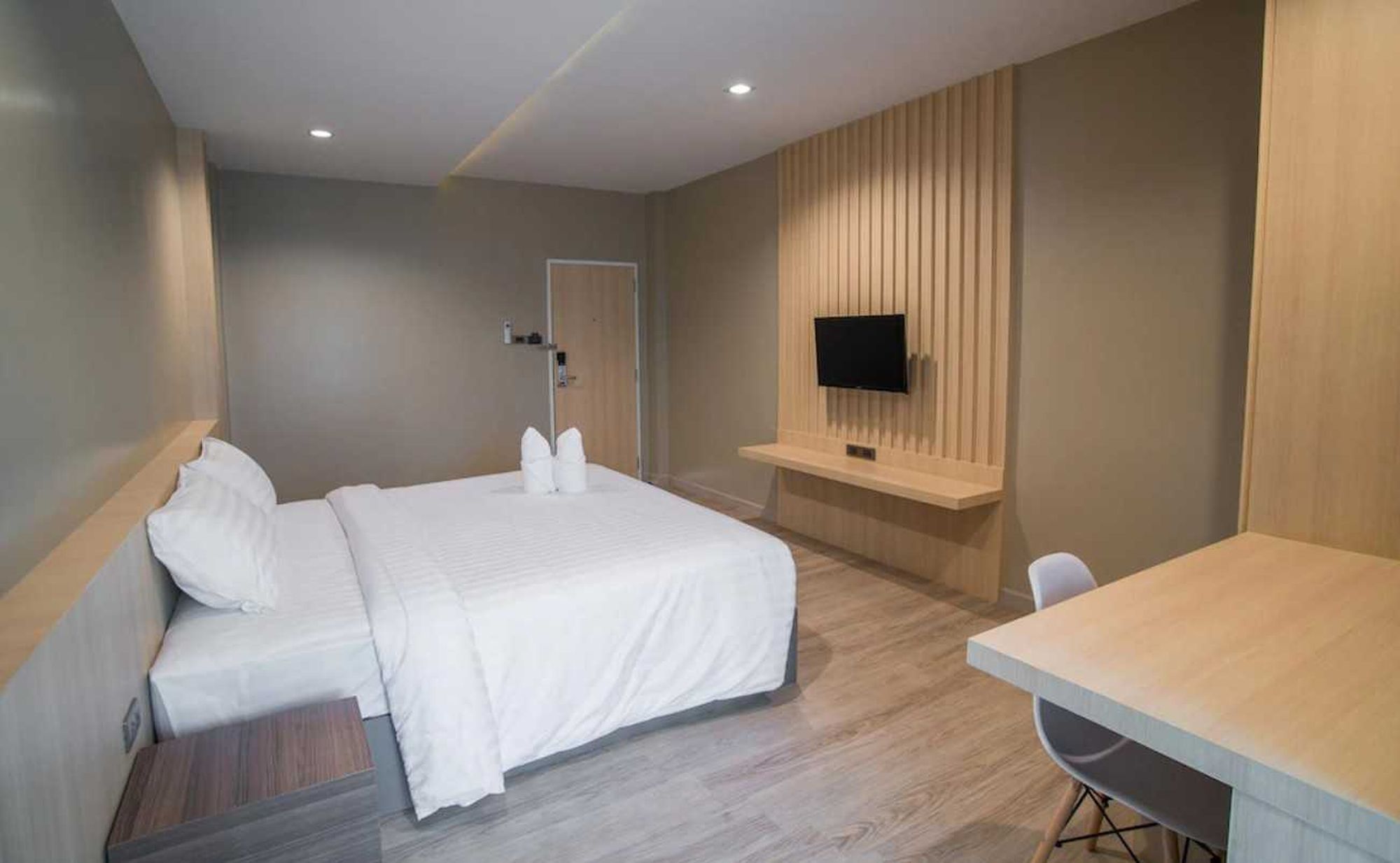 Une chambre d’hôtel comprenant un lit, un bureau, une chaise, un téléviseur fixé au mur et une porte.