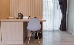 Una pequeña kitchenette con cubierta de madera, una tetera, una taza y un bote de basura.