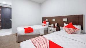 A hotel room with two beds, a wooden headboard, a bedside table with a phone, and a door. - Palette La Route Residence Pattaya (Muang Pattaya)