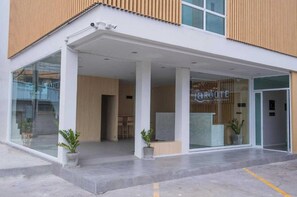 Una entrada de edificio moderna con un mostrador de recepción, puertas de cristal y plantas en macetas.