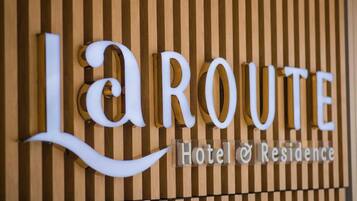 A sign with the name 'La Route Hotel & Residence' against a wooden background.