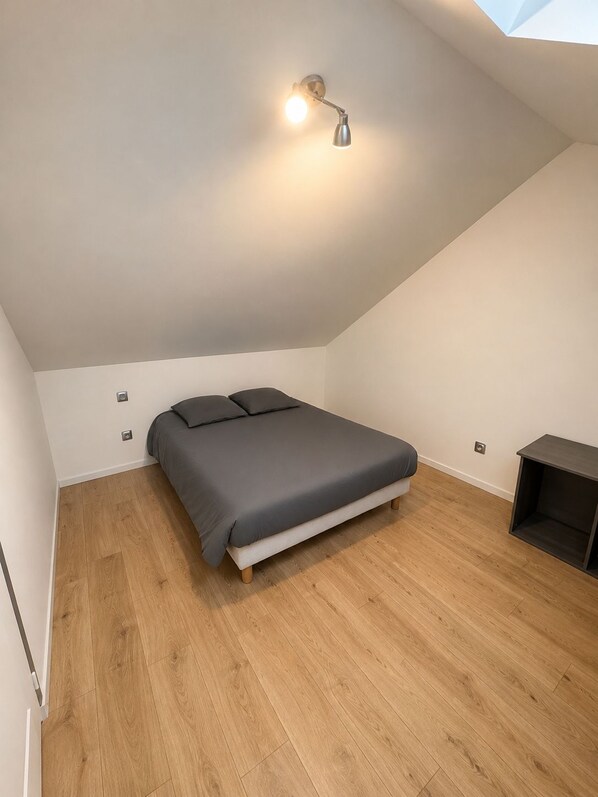 A bedroom with a bed, a bedside table, and a ceiling light fixture.