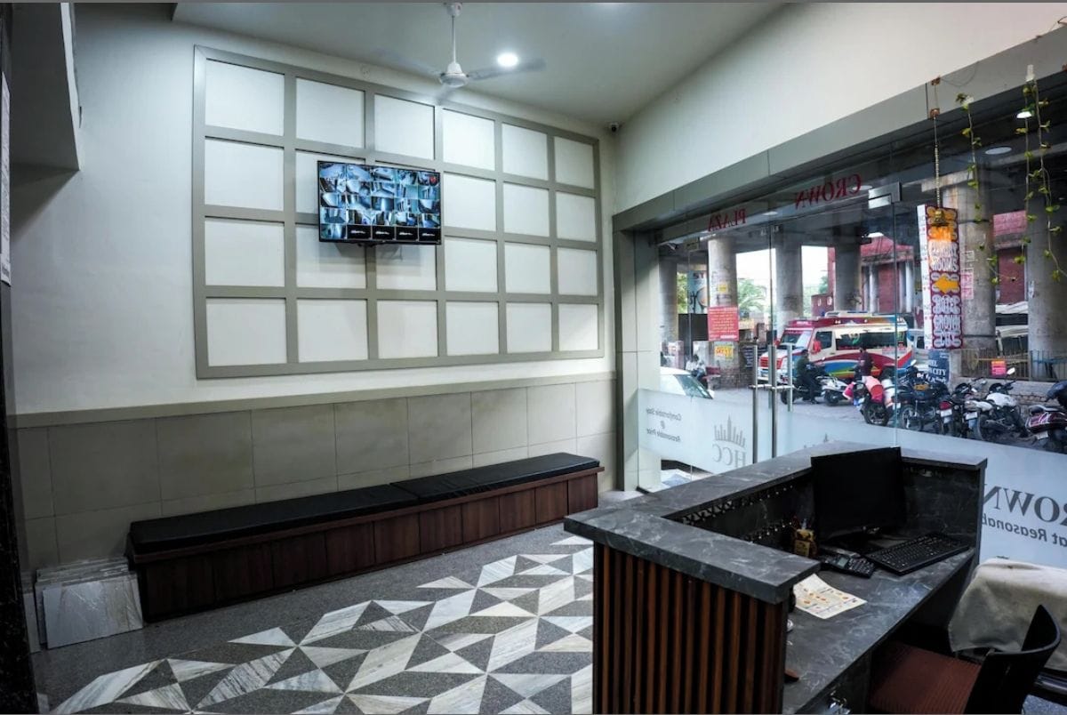 Un área de recepción con piso de baldosas, un banco, un mostrador de recepción y un televisor fijado en la pared.