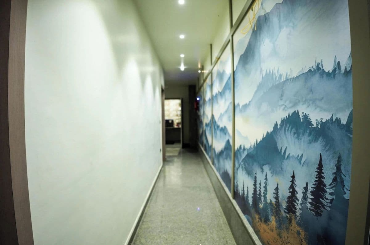 A hallway with a mural of a mountain landscape on the right wall.