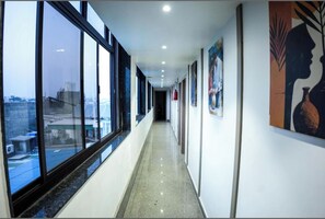Un pasillo con ventanas amplias, obras de arte en las paredes y vistas a la ciudad.