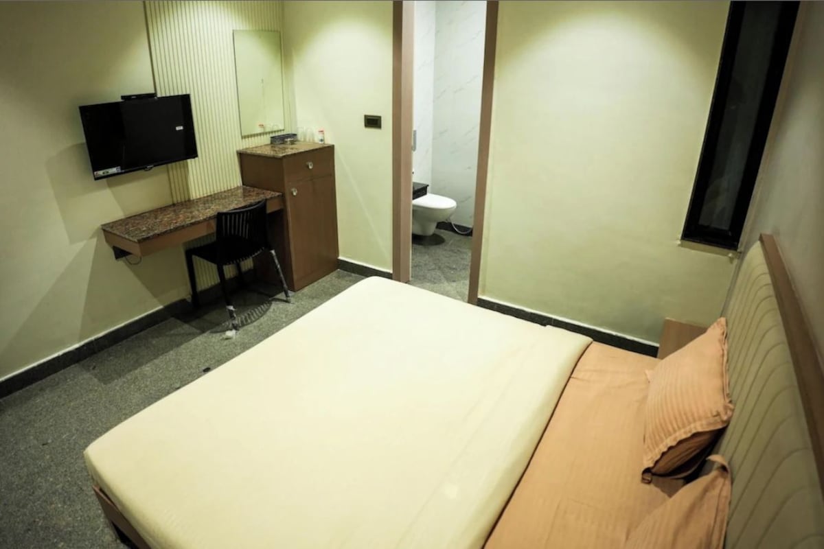 Habitació d'hotel amb un llit, una taula de treball, una cadira, televisió i bany.