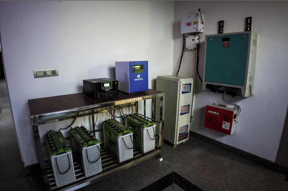 Un panel de control con un dispositivo azul, un detector de incendios rojo y una caja eléctrica blanca.