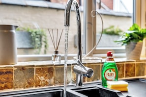 A kitchen sink with running water, a soap dispenser, and a bottle of Fairy dish soap. - Spacious Stoke Townhouse 3BR  Near Hospital & M6 (Stoke-on-Trent)