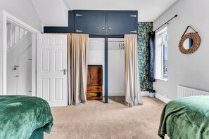 Ein Schlafzimmer mit zwei Betten, einem Kleiderschrank, einer Heizung und einem Fenster mit Vorhang.
