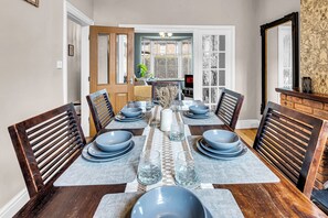 Comedor con mesa de madera dispuesta para seis personas, rodeado de sillas.