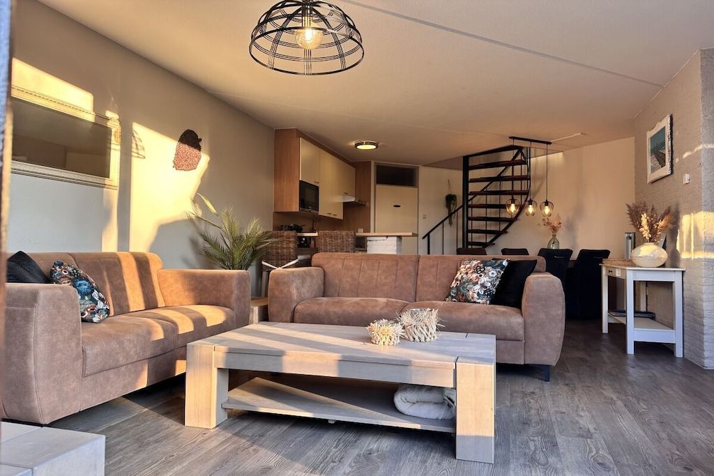 A modern living room with a sofa set, a coffee table, and a staircase leading to an upper floor.