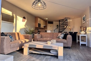 A modern living room with a sofa set, a coffee table, and a staircase leading to an upper floor. - Holiday home in Brouwershaven with barbecue (Brouwershaven)