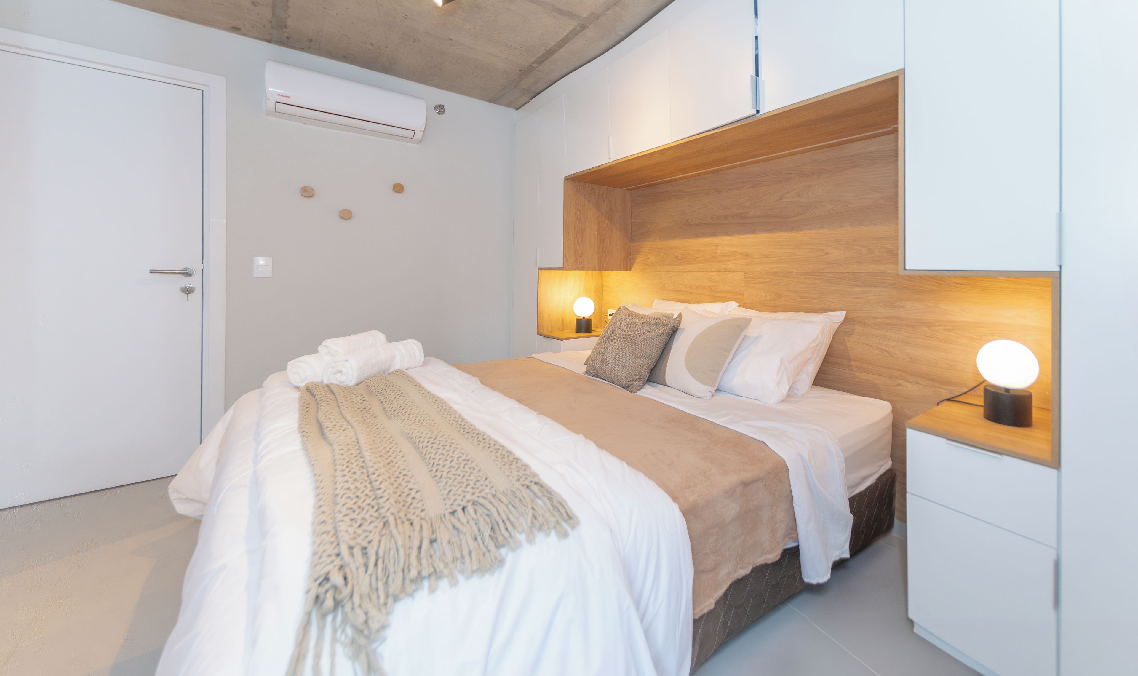 Une chambre à coucher moderne avec un lit, des lampes de chevet et une tête de lit en bois.