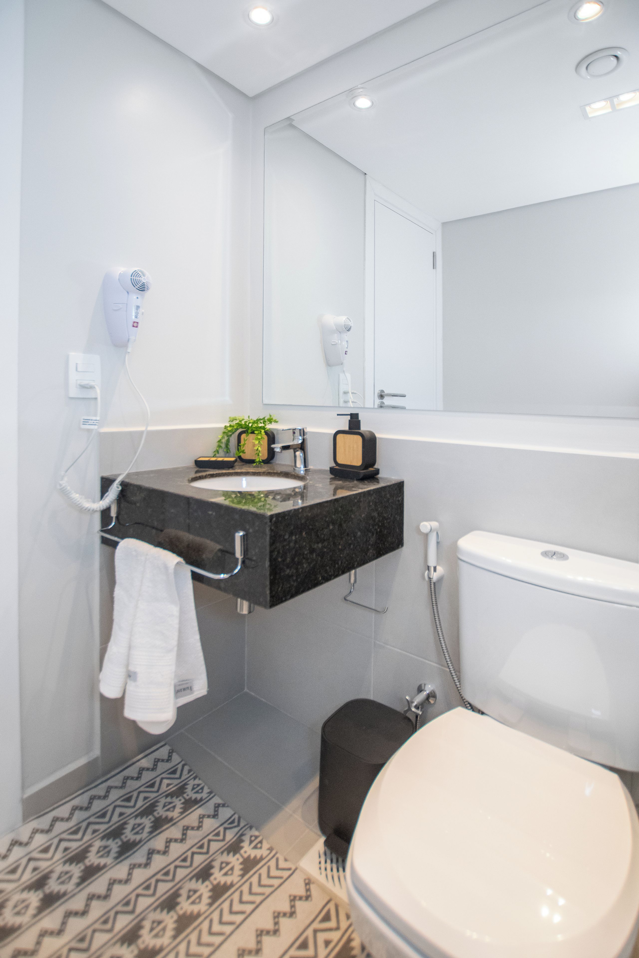 Un bagno moderno con un piano lavabo nero, un water bianco e uno spazio doccia.