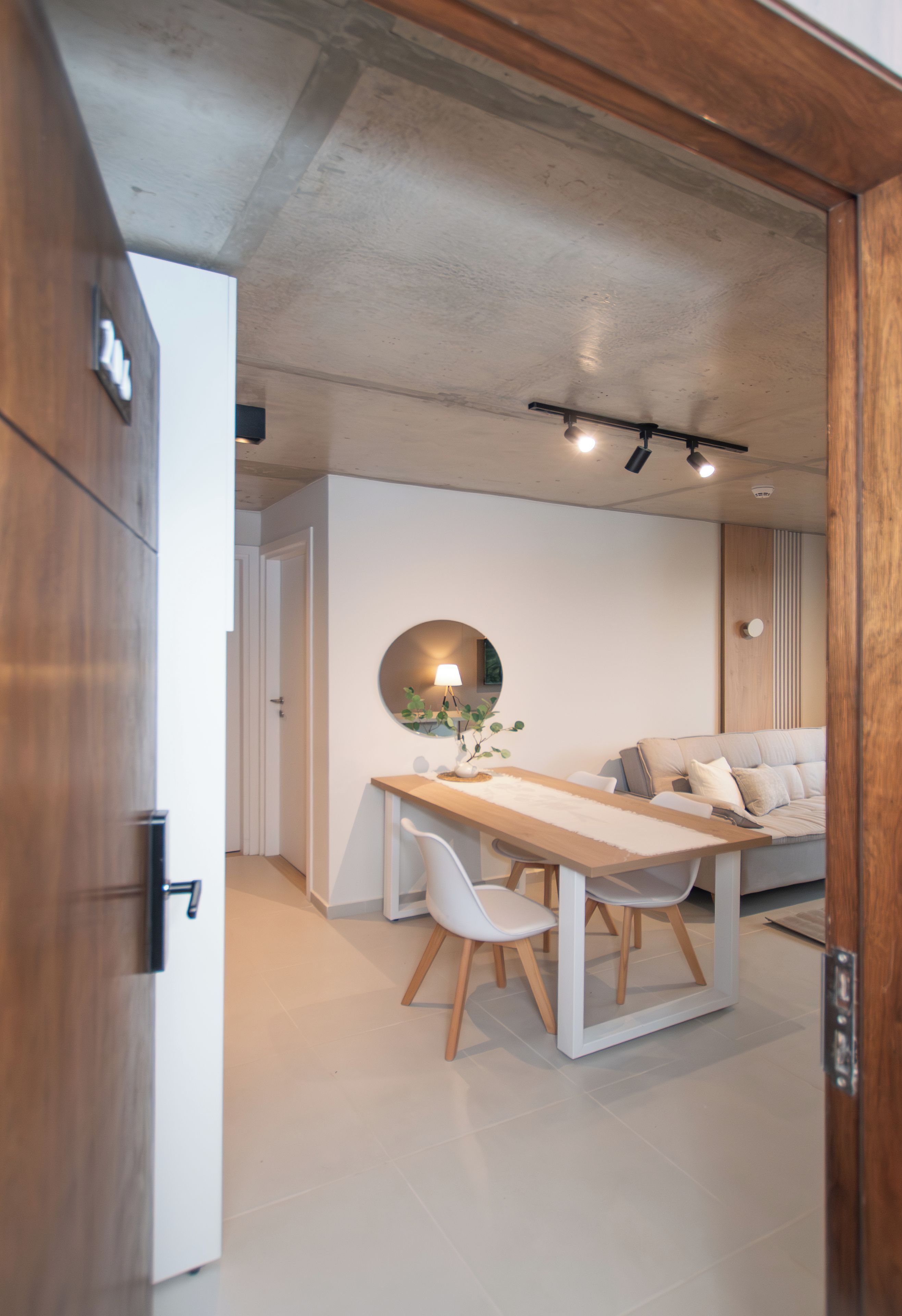 A modern interior with a dining area, a sofa, and a wooden door.