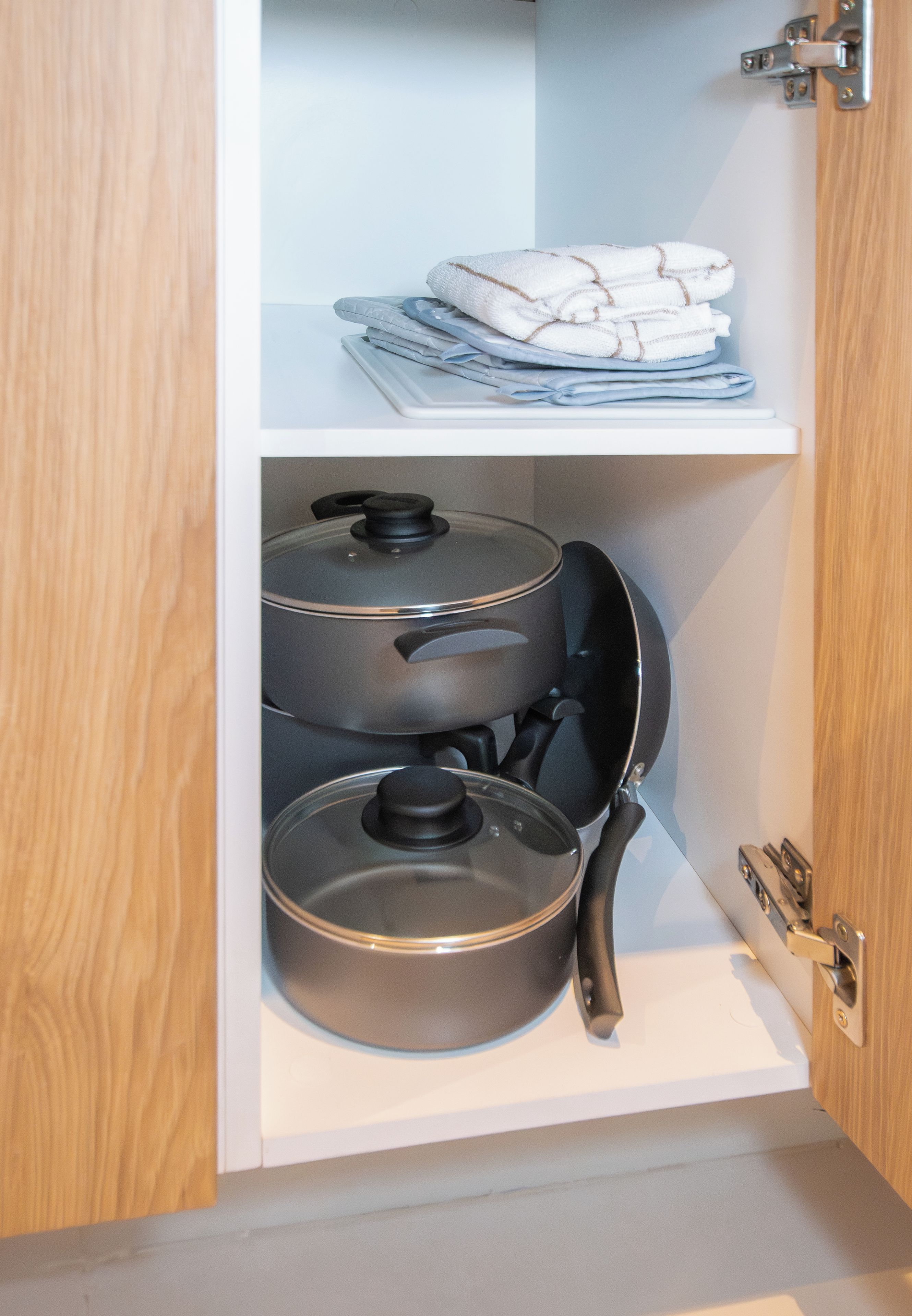 Un armario de cocina con dos ollas y una sartén.