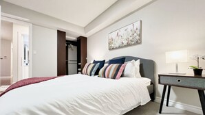 Una habitación de hotel con una cama grande, una mesita de noche con lámpara y un cuadro en la pared.