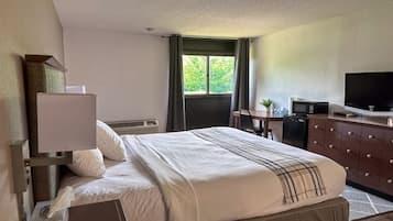 A hotel room with a bed, a desk, a television, and a dresser.