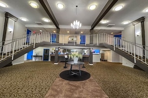 A spacious lobby with a central round table, a chandelier, and a staircase connecting two levels. - 1 King Bed | Mob Acc RI Shwr Nsmk Micfridg (Rochester NY)