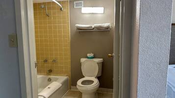 A bathroom with a bathtub, toilet, and a shower area.