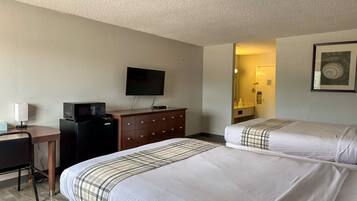 A hotel room with two beds, a desk, a television, and a dresser.