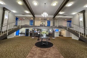 A spacious lobby with a central round table, a chandelier, and a staircase connecting two levels. - 2 Full Beds | Non-Smoking, Micfridge (Rochester NY)