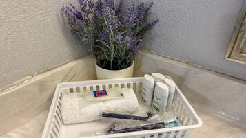 A white plastic basket containing toiletries, a white towel, and a potted lavender plant.