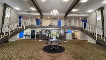 Un hall d’entrée spacieux, doté d’une table ronde centrale, d’un lustre et d’un escalier reliant deux niveaux.