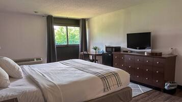 Ett hotellrum med en säng, ett skrivbord, en tv och en byrå.