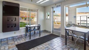 A hotel room with a large window, a flat-screen TV, a small table with chairs, and a tiled floor. - 1 QUEEN BED | NON-SMOKING (The Dalles)