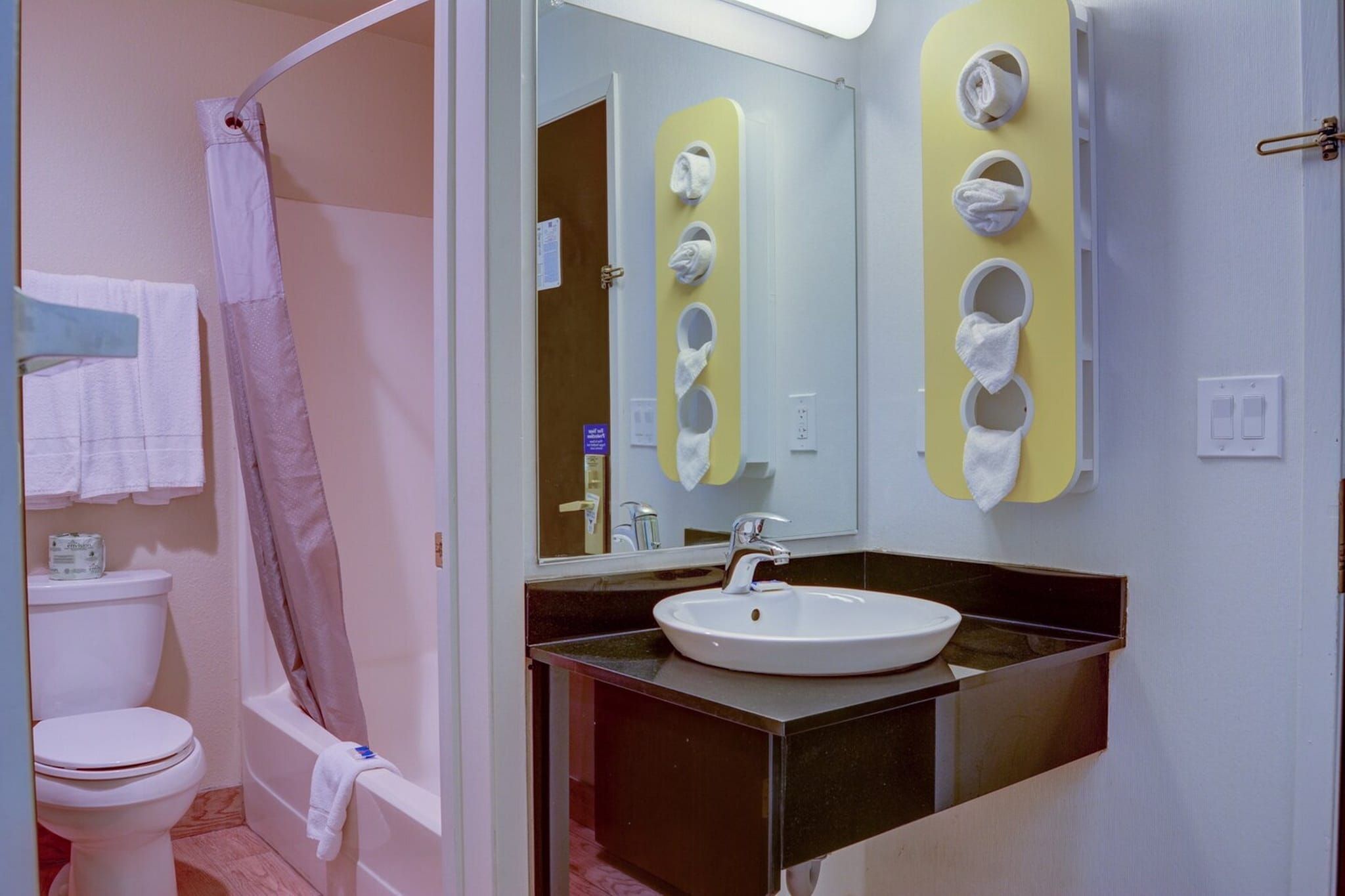 Baño con inodoro, lavamanos, espejo y cortina de ducha.