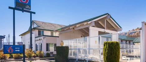 Un motel avec une grande enseigne indiquant le numéro de chambre 6, un espace extérieur abrité et un ciel dégagé.