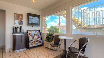 A small hotel room with a kitchenette, a TV, a window with a view of a bridge, and a small table with two chairs.
