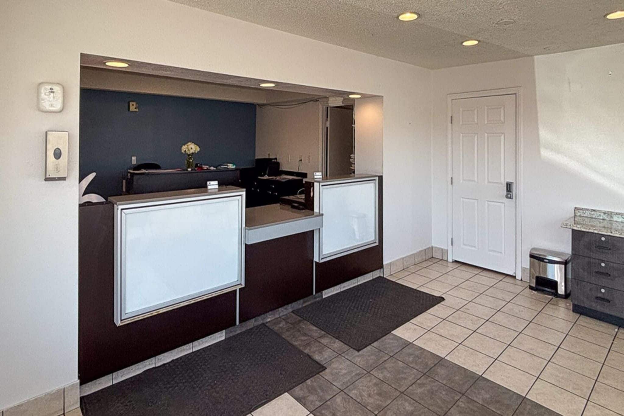 A reception area with two counters, a door, and a trash bin.