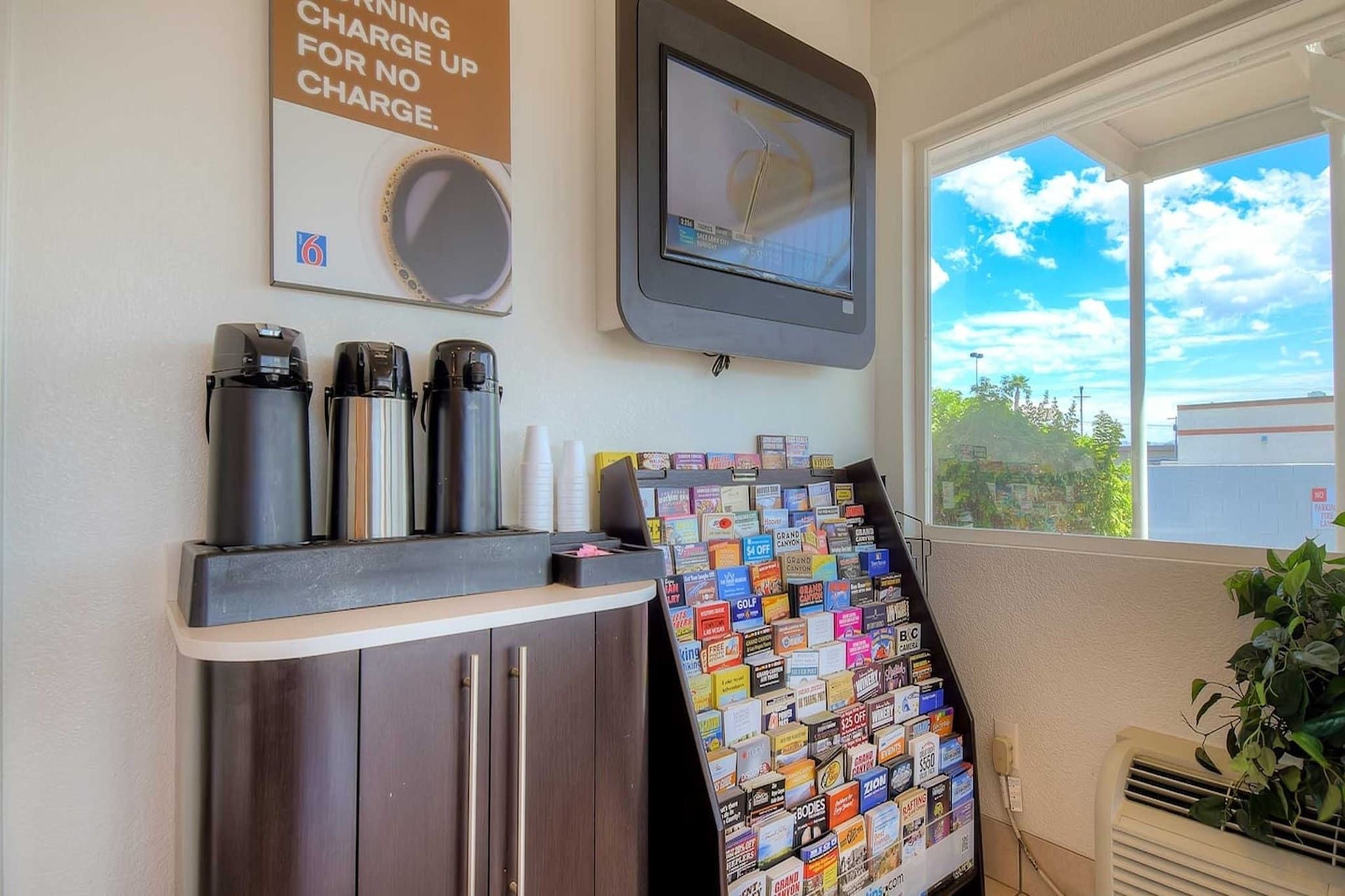 A coffee station with three coffee makers and a sign about charging up for no charge.