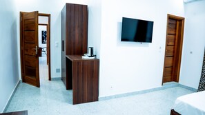 Una habitación de hotel con una cama, un televisor montado en la pared y armarios de madera.