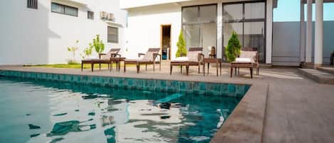 A modern pool area with lounge chairs and a clear blue pool.