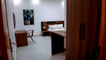 Una habitación de hotel con cama, mesita de noche, silla y un cuadro en la pared.